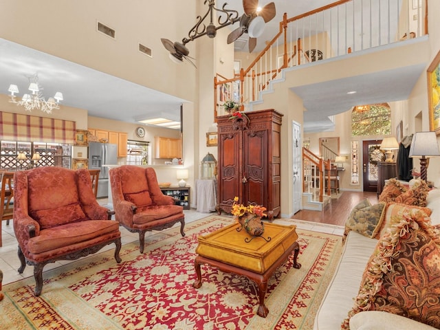 living room with light hardwood / wood-style flooring, a towering ceiling, and a chandelier