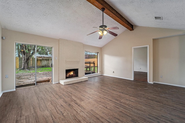 unfurnished living room with a textured ceiling, plenty of natural light, dark hardwood / wood-style floors, and a brick fireplace