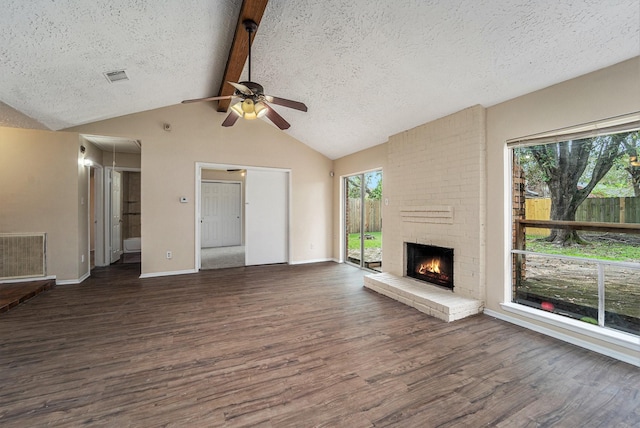 unfurnished living room with a textured ceiling, a fireplace, lofted ceiling with beams, and dark hardwood / wood-style floors