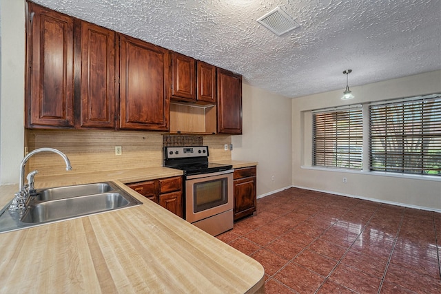 kitchen with sink, dark tile patterned floors, backsplash, decorative light fixtures, and stainless steel range with electric stovetop