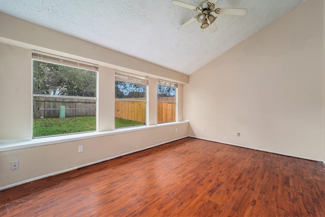 empty room with a textured ceiling, hardwood / wood-style flooring, and a healthy amount of sunlight