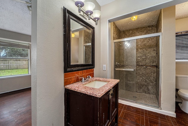 bathroom featuring vanity, a textured ceiling, a shower with door, wood-type flooring, and toilet