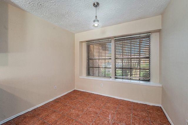 empty room featuring dark tile patterned floors and a textured ceiling