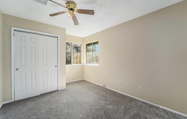 unfurnished bedroom with carpet, ceiling fan, a textured ceiling, and a closet