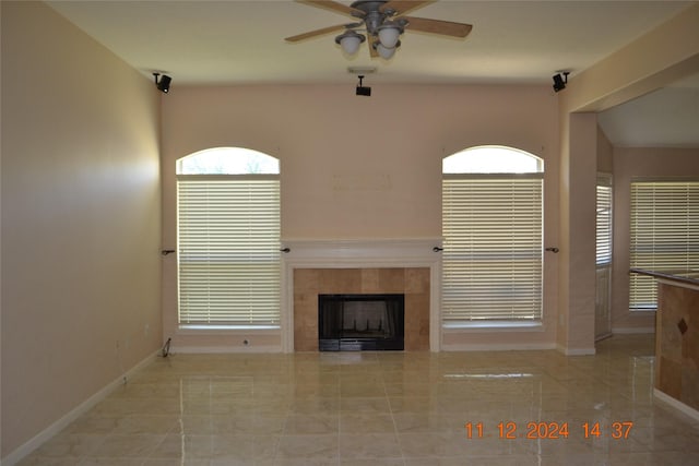 unfurnished living room featuring a tiled fireplace and ceiling fan