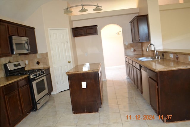 kitchen featuring sink, decorative backsplash, light tile patterned floors, appliances with stainless steel finishes, and a kitchen island