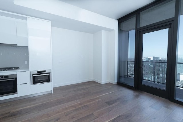 kitchen featuring decorative backsplash, appliances with stainless steel finishes, floor to ceiling windows, dark wood-type flooring, and white cabinets