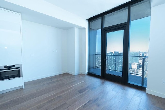 spare room with heating unit, floor to ceiling windows, and dark wood-type flooring