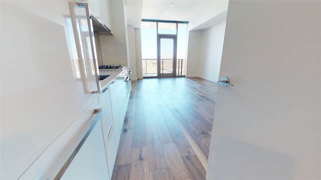 unfurnished living room featuring floor to ceiling windows and light wood-type flooring