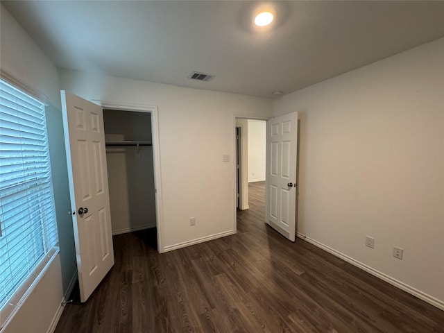 unfurnished bedroom featuring a closet and dark wood-type flooring