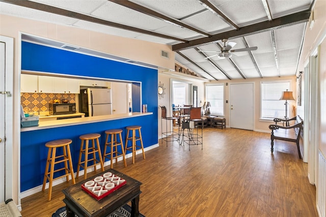 living room with hardwood / wood-style floors, vaulted ceiling with beams, and ceiling fan