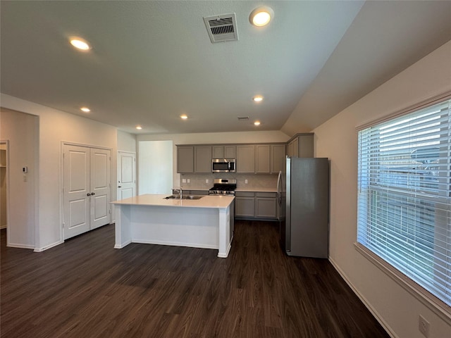 kitchen with sink, dark hardwood / wood-style flooring, an island with sink, gray cabinets, and appliances with stainless steel finishes