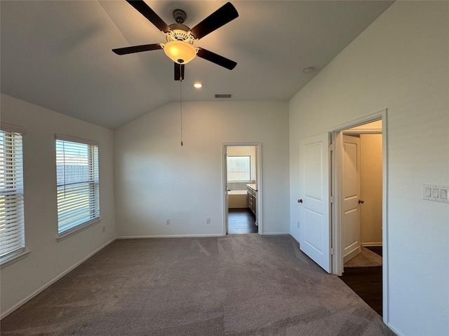 unfurnished bedroom with ceiling fan, lofted ceiling, and dark colored carpet