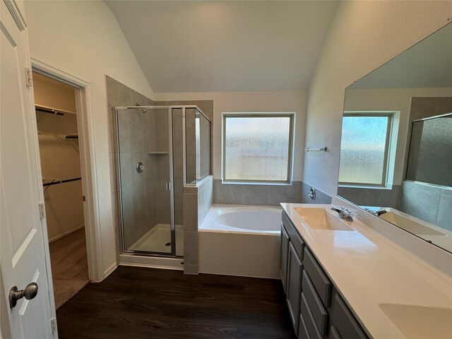 bathroom featuring wood-type flooring, vanity, shower with separate bathtub, and vaulted ceiling