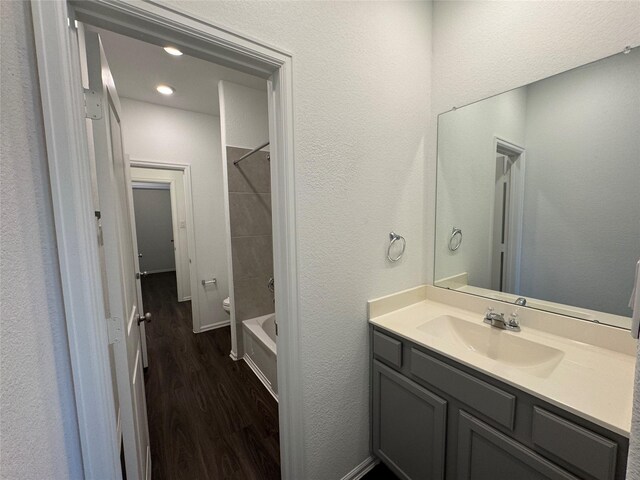 full bathroom with hardwood / wood-style flooring, vanity,  shower combination, and toilet