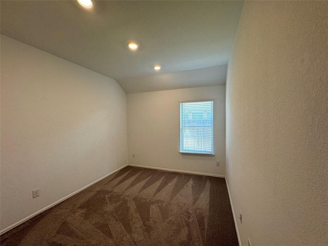 carpeted spare room with vaulted ceiling