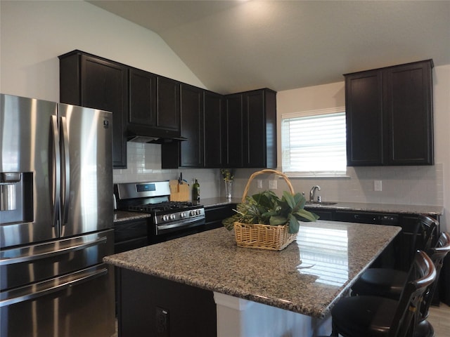 kitchen with lofted ceiling, stone counters, a kitchen island, a kitchen bar, and stainless steel appliances