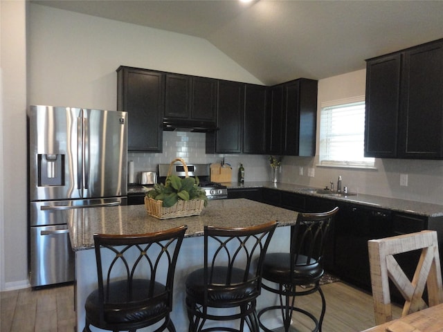 kitchen featuring a center island, dark stone countertops, lofted ceiling, and appliances with stainless steel finishes