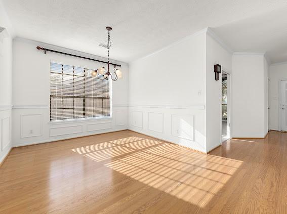 unfurnished dining area with crown molding, hardwood / wood-style flooring, and a notable chandelier