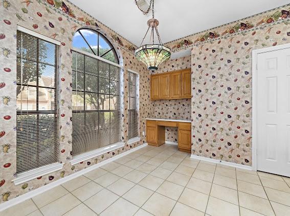 kitchen featuring pendant lighting, light tile patterned floors, and built in desk