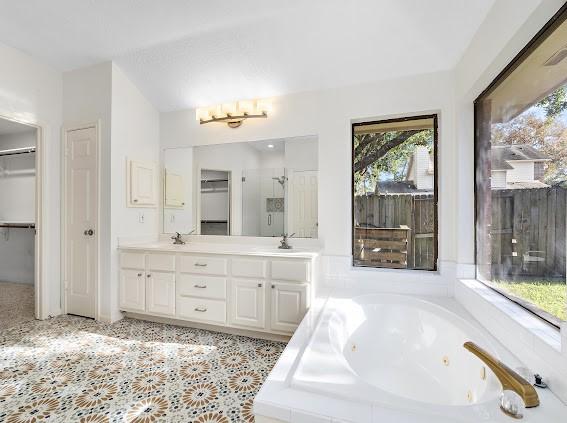 bathroom featuring vanity and tiled bath