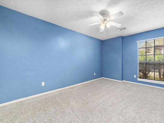 spare room featuring carpet flooring, a textured ceiling, and ceiling fan