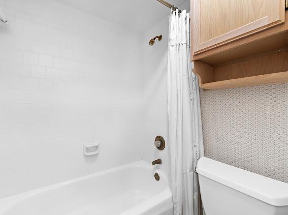 bathroom featuring shower / bath combination with curtain and toilet