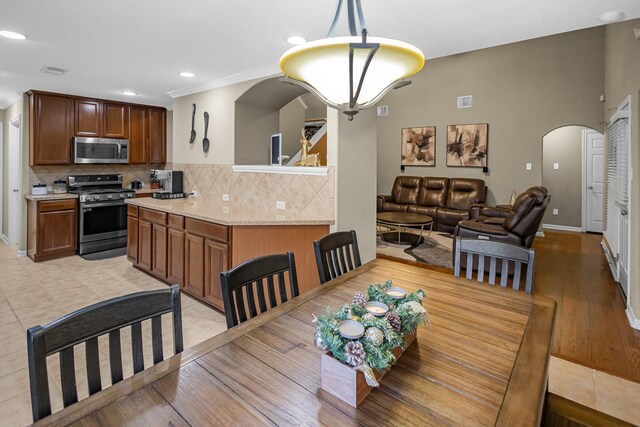 dining space featuring ornamental molding and light hardwood / wood-style flooring