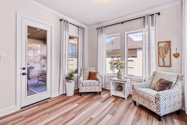 living area featuring light hardwood / wood-style flooring, a healthy amount of sunlight, and crown molding