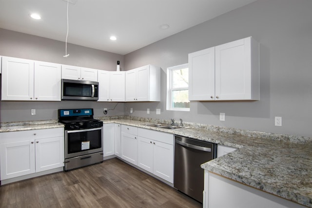 kitchen with sink, dark hardwood / wood-style floors, light stone countertops, white cabinetry, and stainless steel appliances