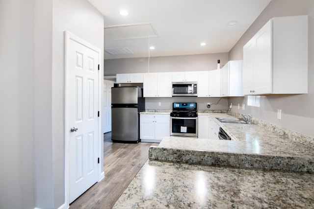 1709 Stevens St, Houston, TX 77026 - kitchen with stainless steel appliances, light wood-style floors, light stone countertops, and white cabinets