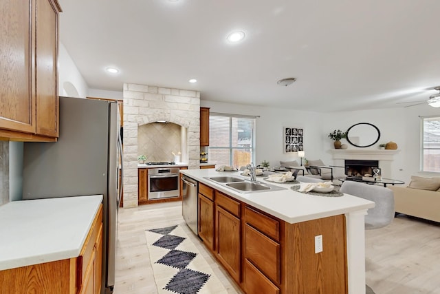 kitchen featuring stainless steel appliances, sink, an island with sink, and light hardwood / wood-style flooring