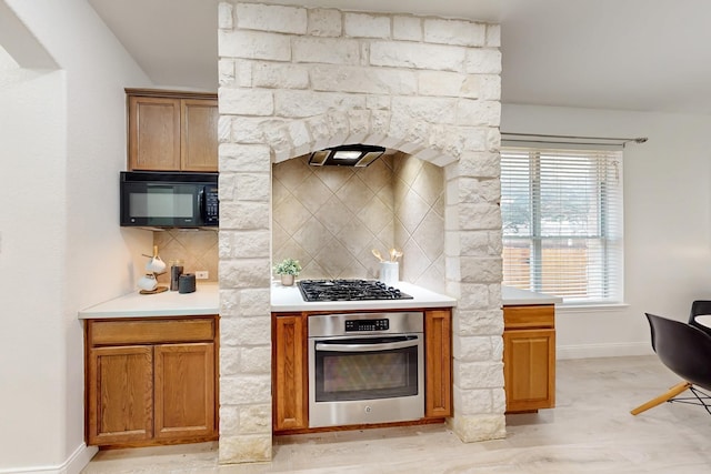 kitchen with backsplash, stainless steel appliances, and light hardwood / wood-style floors