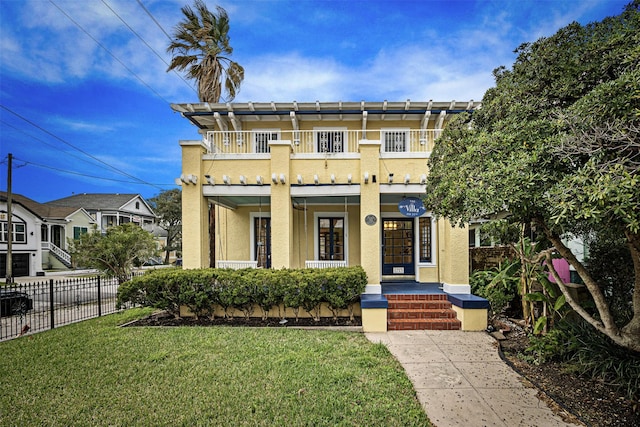 view of front of house featuring a balcony, covered porch, and a front yard