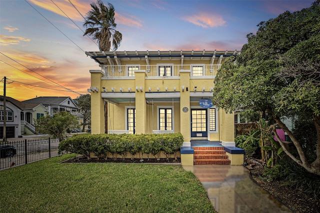 view of front of house featuring a balcony and a yard