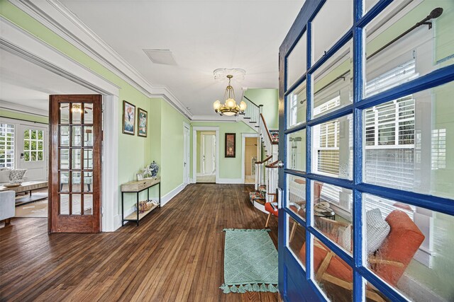 hallway featuring a notable chandelier, dark hardwood / wood-style flooring, ornamental molding, and french doors