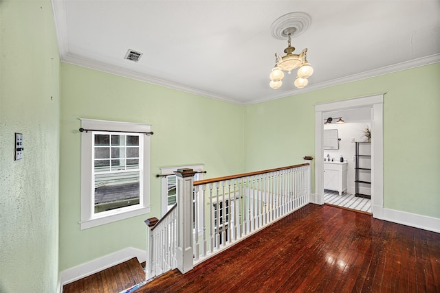 hall featuring dark hardwood / wood-style floors, crown molding, and an inviting chandelier