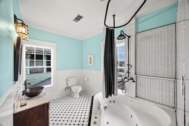 full bathroom with tiled shower / bath combo, a textured ceiling, toilet, vanity, and ornamental molding