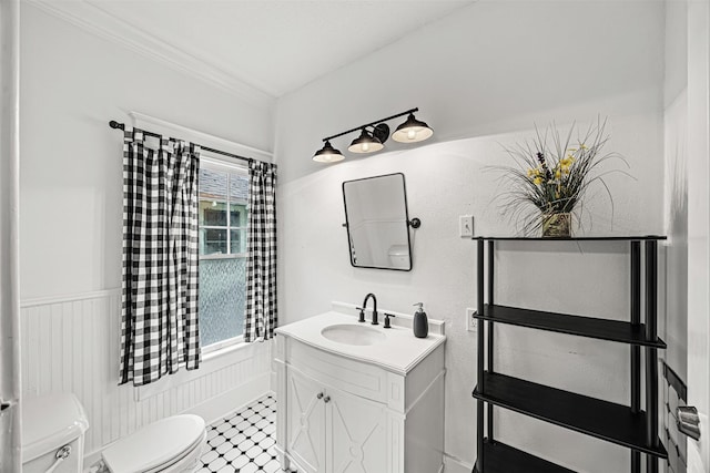 bathroom with toilet, vanity, and ornamental molding