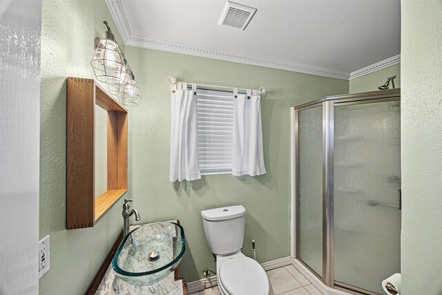 bathroom featuring tile patterned floors, toilet, a shower with shower door, and ornamental molding