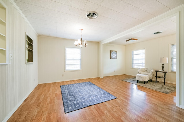 unfurnished room featuring ornamental molding, light hardwood / wood-style floors, a wealth of natural light, and a notable chandelier