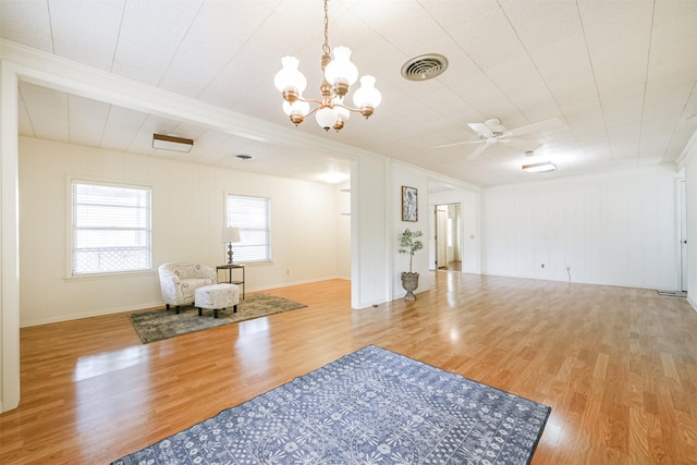 living area with ceiling fan with notable chandelier and light hardwood / wood-style floors