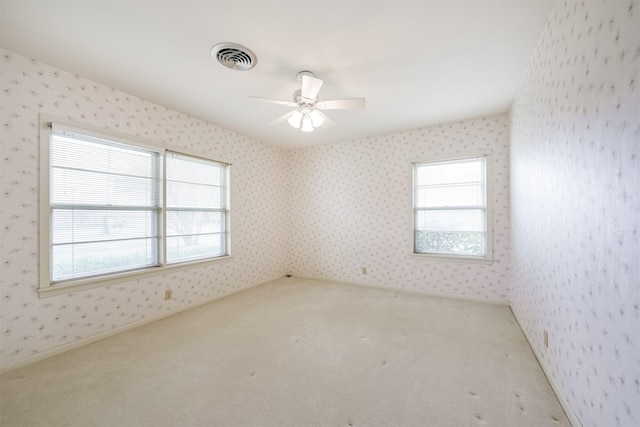 empty room with carpet, ceiling fan, and a healthy amount of sunlight