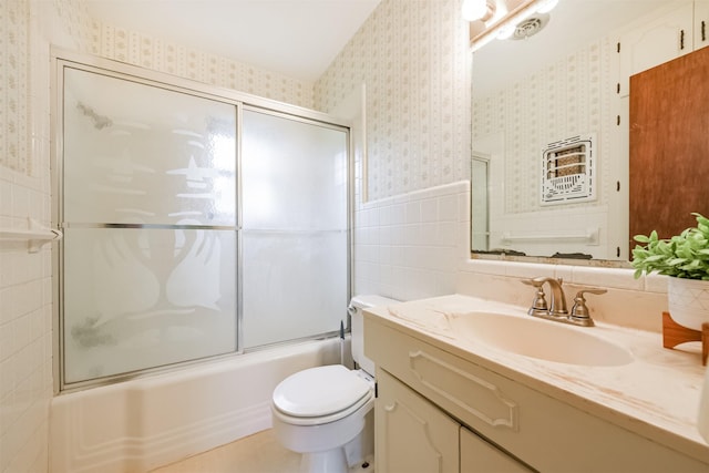 full bathroom featuring vanity, toilet, tile walls, and bath / shower combo with glass door