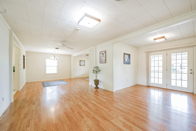 spare room with ceiling fan with notable chandelier and light wood-type flooring