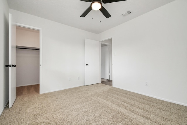 unfurnished bedroom with ceiling fan, light colored carpet, a spacious closet, and a closet