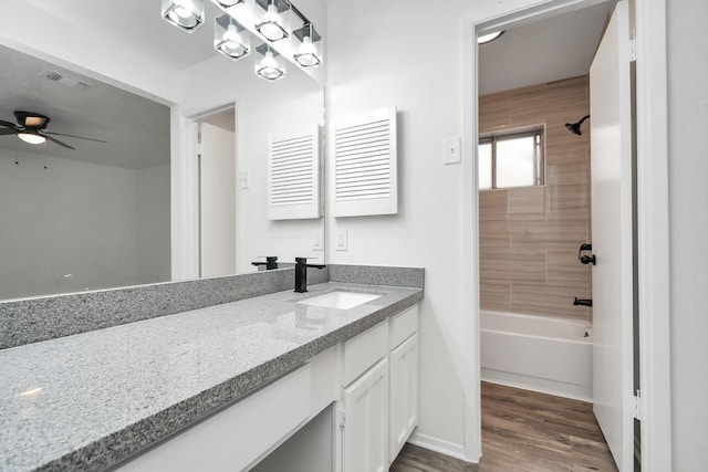 bathroom featuring wood-type flooring, vanity, tiled shower / bath combo, and ceiling fan