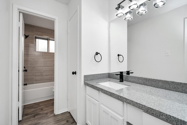 bathroom featuring wood-type flooring, vanity, and tiled shower / bath