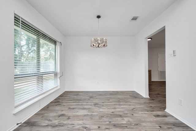 unfurnished dining area with wood-type flooring and a chandelier