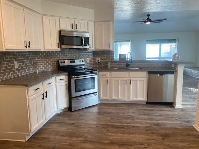 kitchen featuring appliances with stainless steel finishes, dark hardwood / wood-style flooring, white cabinetry, and sink